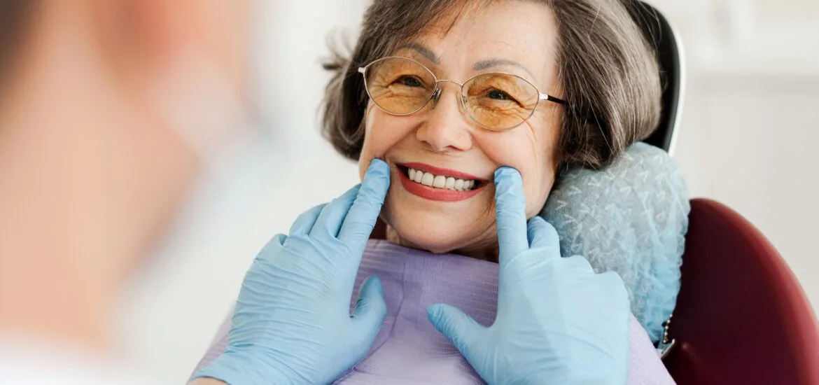 Smiling, happy, beautiful senior woman sitting in dental chair after denture treatment