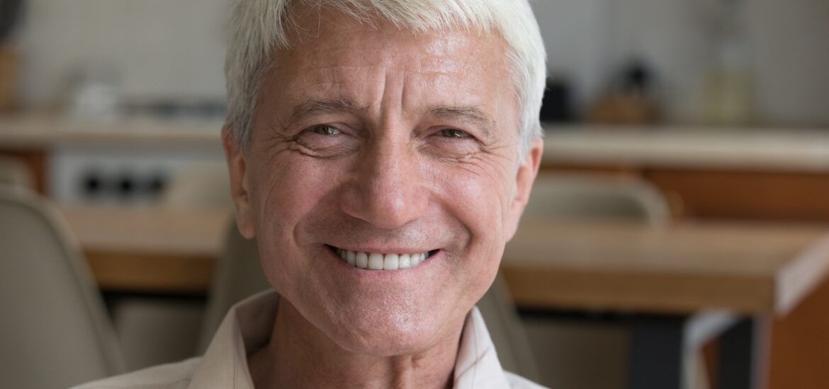 head shot of older man, smiling showing new dentures
