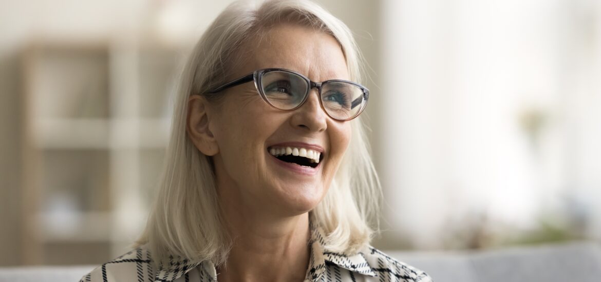 mature woman smiling on couch, perfect new dental implants