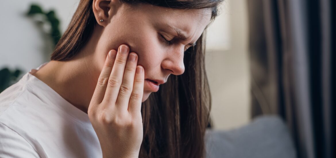 young woman holding her jaw suffering from wisdom teeth pain