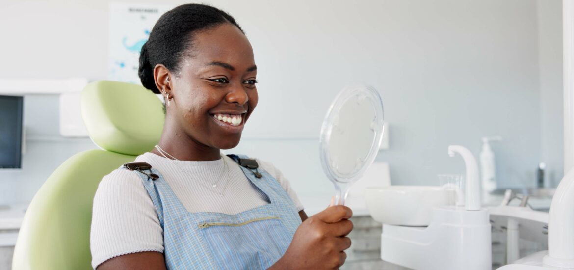 happy woman looking in a mirror, new dental veneers